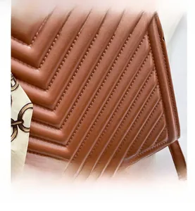 Detail of brown leather bag featuring V-quilted pattern and decorative silk scarf