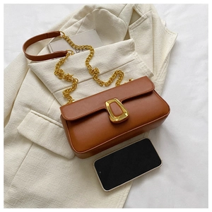 Detail of a brown leather shoulder bag with gold geometric buckle and chain on a suit