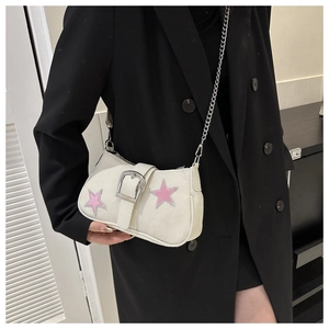 Detail of cream underarm bag with pink star patches and silver chain strap on black blazer