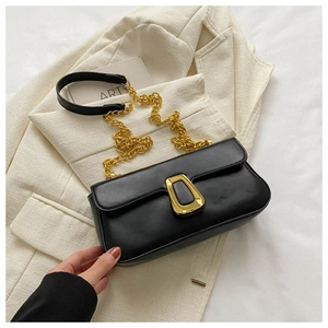 Detail view of the black leather bag featuring a gold chain strap and metal buckle