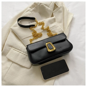 Detail of minimalist black leather crossbody bag with gold chain strap and chunky metal lock