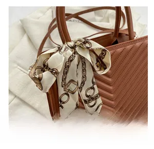 Close-up of brown quilted leather crossbody bag featuring a silk scarf on the handle