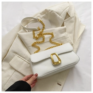 Detail of white chain bag featuring a gold trapezoid clasp and smooth leather texture