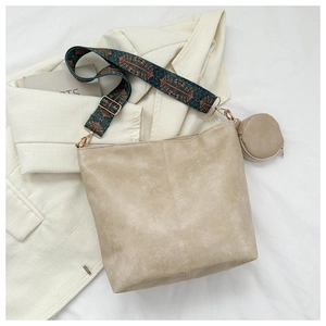 Detail of beige tote with geometric strap and mini round purse on a blazer