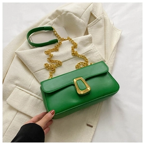Detail of green leather shoulder bag featuring gold chain strap and trapezoid buckle