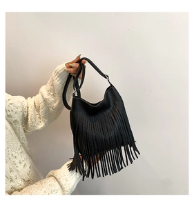 Detail of black pebbled leather bucket bag featuring long fringe and adjustable strap