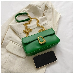 Close-up of green leather chain bag with gold hardware and phone for size reference