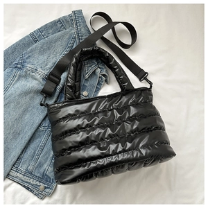 Detail of black quilted puffer tote bag with glossy finish and adjustable shoulder strap