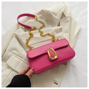 Detail of hot pink leather bag featuring a chunky gold chain strap and metallic buckle