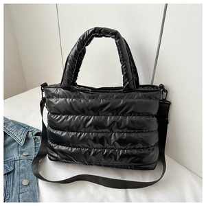 Detail of black quilted puffer tote bag featuring plush handles and adjustable nylon strap