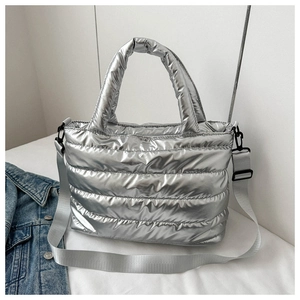 Detail of silver metallic quilted tote bag with top handle and adjustable strap