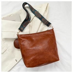 Detail of vintage brown shoulder bag with a colorful ethnic style wide strap and mini coin purse