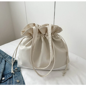 Detail of off-white canvas drawstring bag featuring textured stitching and long straps