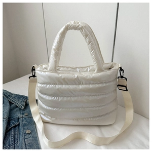 Detail of white quilted puffer bag featuring high-shine texture and adjustable strap
