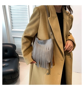 Detail of grey fringe crossbody bag with lychee grain texture on a camel coat
