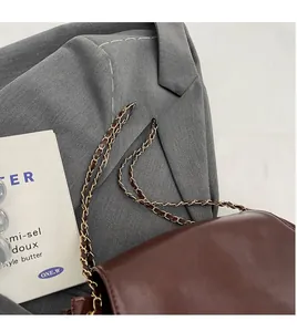 Detailed view of brown leather bag with glossy finish and elegant golden hardware chain