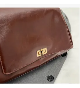 Close-up of deep brown oil wax leather handbag with golden hardware clasp detail