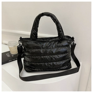 Detail of black quilted puffer tote bag with glossy finish and detachable wide shoulder strap