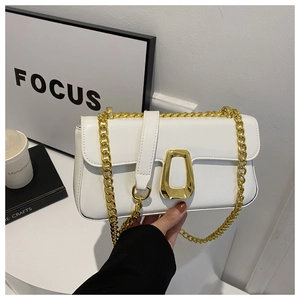 Detail view of white leather crossbody bag with bold gold chain and geometric metal buckle
