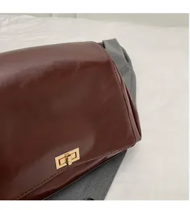 Detail of dark brown leather bag showing smooth texture, neat stitching and gold clasp