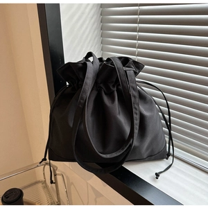 Close-up of black canvas drawstring bucket bag featuring a natural pleated texture and wide straps