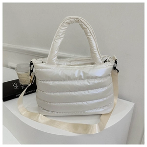 Close-up of quilted cream tote bag with padded handles and adjustable shoulder strap