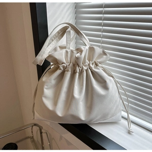 Detail of cream drawstring tote bag showing pleated edges and soft natural light shadows