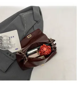 Macro view of open deep red chain bag showing spacious interior with daily essentials