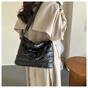 Quilted black puffer tote bag with adjustable strap and shiny nylon finish for winter