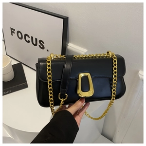Detailed view of black leather bag with gold geometric lock and metal chain strap