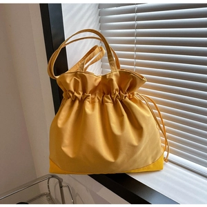 Detail of bright yellow drawstring tote bag with wide handles on a window sill