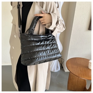 Detail of black quilted down tote bag featuring glossy waterproof fabric and shoulder strap
