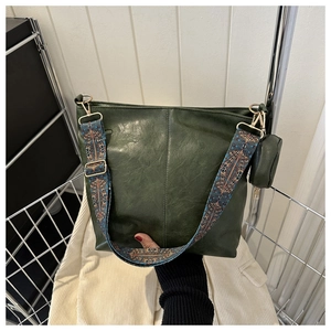 Detail of dark green leather tote with a colorful geometric ethnic shoulder strap