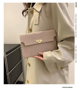 Detail of beige crocodile embossed clutch with golden rectangular twist lock closure
