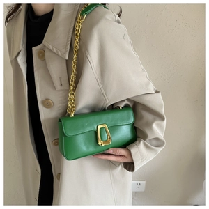 Close-up of green leather shoulder bag with gold chain and buckle on beige coat