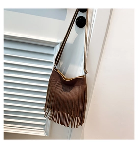 Detail of dark brown lychee leather texture and long tassel design on a shoulder bag
