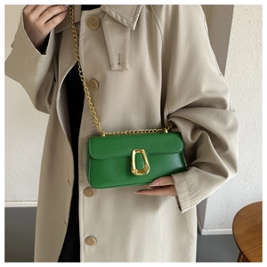 Close-up of vibrant green leather shoulder bag with gold chain and metal buckle