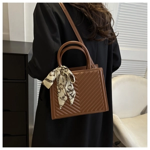 Brown quilted crossbody bag featuring elegant chevron stitching and silk scarf on handle