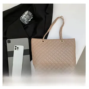 Detail of beige quilted tote bag with gold chain strap and elegant diamond stitching