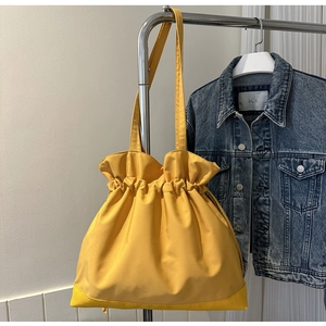 Detail of ginger yellow nylon tote bag featuring reinforced bottom and drawstring closure