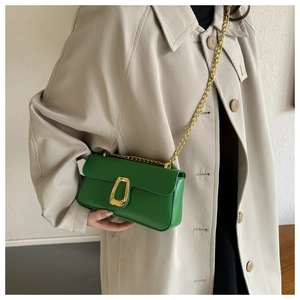 Close-up of bright green leather chain bag featuring a large gold buckle on smooth texture