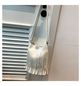Detail of white lychee leather texture and long bohemian fringes on the crossbody bag