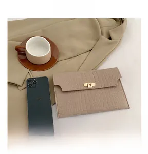 Detail of khaki faux crocodile skin envelope clutch bag with gold metallic buckle closure