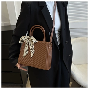 Sac à main matelassé marron avec foulard en soie porté par un mannequin en costume