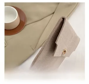 Side view of beige felt envelope clutch with gold twist lock and layered structure