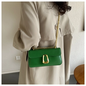 Detail of emerald green leather bag featuring a unique gold-tone metal clasp and chain