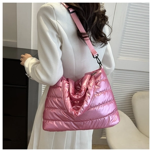 Pink metallic quilted puffer tote bag with adjustable strap worn by model in a room