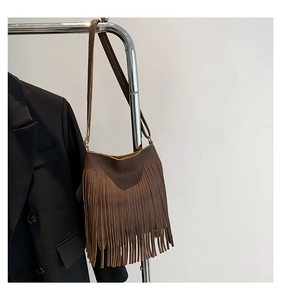 Detailed close-up of dark brown lychee leather handbag with long vertical tassels