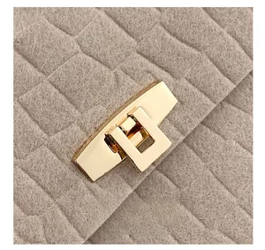 Detail of light gold polished metal lock on felt fabric with square quilted texture