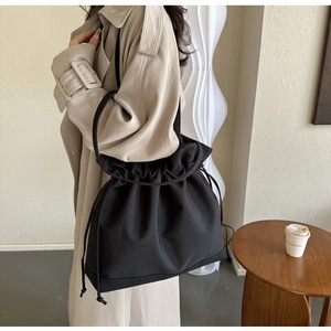 Detail of minimalist black nylon drawstring tote bag on a wooden table in a cafe
